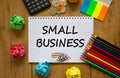 Small business symbol. White note with inscription `small business` on beautiful wooden table, colored paper, colored pencils, Royalty Free Stock Photo