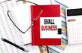 SMALL BUSINESS text on notebook with chart, calculator and pen Royalty Free Stock Photo