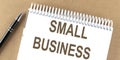 SMALL BUSINESS text on a notepad with pen, business Royalty Free Stock Photo