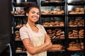 Small Business. Young woman in apron at bakery shop crossed arms posing to camera cheerful Royalty Free Stock Photo