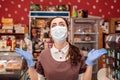 Small businesses during the pandemic. A female worker in a medical mask and rubber gloves, spreads her hands and looks up with Royalty Free Stock Photo