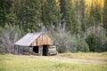 A small cabin in the woods with a grassy field in the background Royalty Free Stock Photo