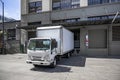 Small cabover rig semi truck with box trailer loading cargo standing in the warehouse dock on the city street