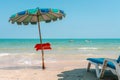 Small cafe menu table under a beach umbrella stands in front of seashore line, sun beach lounge chair, two jetski Royalty Free Stock Photo