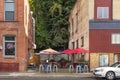 A small cafe patio with colorful umbrellas is sandwiched between two brick buildings in the historic town of Wallace, Idaho