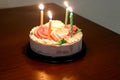 Small cake on wooden table wit lighted candles