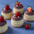 Small cakes topped with chocolate frosting and strawberries, complimentary