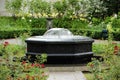 Small calm park fountain surrounded by flowers