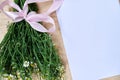 Small camomiles bouquet tied with pink ribbon and white paper sheet on wooden table. Natural background picture of wild flowers. Royalty Free Stock Photo