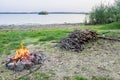 Small campfire with flames beside a lake with wood pile on the side Royalty Free Stock Photo
