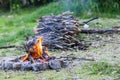 Small campfire with flames beside a lake with wood pile on the side Royalty Free Stock Photo