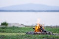 Small campfire with flames beside a lake Royalty Free Stock Photo
