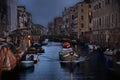 small canal with little boat with people with red umbrella and old houses in row on dusk in rainy day in Venice, Italy Royalty Free Stock Photo