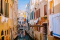 A small canal street in Venice. Old houses with Windows facing the canal. Italian flavor in Venice. Clothes drying on a Royalty Free Stock Photo