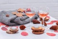 Small candles, two glasses with rose wine, cones, dry red leaves, a gray scarf knitted on a white wooden table. Royalty Free Stock Photo