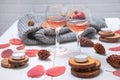 Small candles, two glasses with rose wine, cones, dry red leaves, a gray scarf knitted on a white wooden table Royalty Free Stock Photo