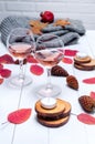 Small candles, two glasses with rose wine, cones, dry red leaves, gray scarf knitted on a white wooden table. Royalty Free Stock Photo