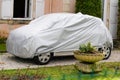 Small car with grey silver cover in the street