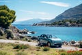 A small car journeying along a picturesque road that winds beside the stunning sea coast of the Riviera