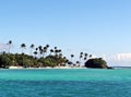 Small Caribbean island with palm trees on a white sandy beach and azure ocean water