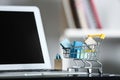 Small cart with paper bags and laptop on glass table. Online shopping Royalty Free Stock Photo