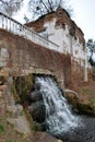 A small cascading waterfall near the ruins of an old house and a fence in an ancient park Royalty Free Stock Photo