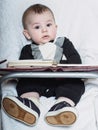 Small caucasian baby boy sitting in chear with notepad