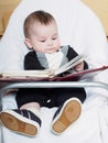 Small caucasian baby boy sitting in chear with notepad Royalty Free Stock Photo