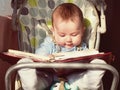 Small caucasian baby boy sitting in chear with notepad