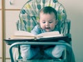 Small caucasian baby boy sitting in chear with notepad