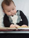 Small caucasian baby boy sitting in chear with notepad