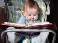 Small caucasian baby boy sitting in chear with notepad Royalty Free Stock Photo