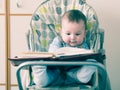 Small caucasian baby boy sitting in chear with notepad