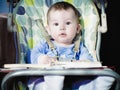 Small caucasian baby boy sitting in chear with notepad