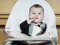 Small caucasian baby boy sitting in chear with notepad