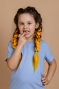 Small Caucasian child with finger pointing at mouth showing missing tooth which hurts looking at camera having kanekalon