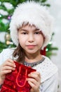 Small Caucasian girl in white fur Santa hat holding red gift bag in hands Royalty Free Stock Photo