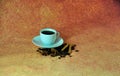 A small ceramic cup with freshly brewed coffee on a white saucer, standing in a scattering of coffee beans, cinnamon sticks and Royalty Free Stock Photo