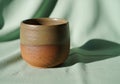 A small ceramic cup on a light green fabric backdrop. The cup Royalty Free Stock Photo