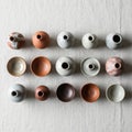 Of small ceramic vessels arranged in a 4x4 grid on a textured Royalty Free Stock Photo