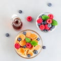 Small cereal pancakes in a glass bowl, with maple syrup, raspberry, blueberry and milk, horizontal, top view, square format Royalty Free Stock Photo