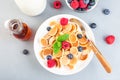 Small cereal pancakes with maple syrup, raspberry, blueberry and milk, in white bowl, horizontal, top view Royalty Free Stock Photo