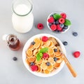 Small cereal pancakes with maple syrup, raspberry, blueberry and milk, in  white bowl, horizontal, top view, square Royalty Free Stock Photo