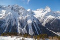 Small chair ski-lift in a coniferous forest against the backdrop of the Caucasus Mountains range near the town of Dombai, Russia Royalty Free Stock Photo