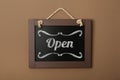 Small chalk board with word Open on brown wall