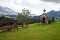 Small chapel in the middle of the mountain landscape of the Alps. In the foreground you can see another wooden fence Royalty Free Stock Photo