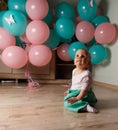 A small, charming child, a girl, celebrates her first birthday, sitting next to her with balloons. Children`s Party Organization. Royalty Free Stock Photo