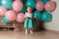 A small, charming child, a girl, celebrates her first birthday, sitting next to her with balloons. Children`s Party Organization. Royalty Free Stock Photo