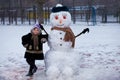 A small cheerful girl near big funny snowman