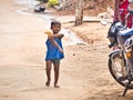 Small child alone on the street holding bag of chips in hand. Dalit boy, very poor indian